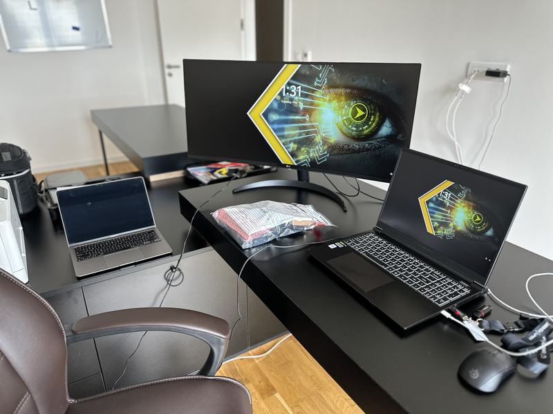 A forensic workstation with an ultrawide display, laptop and imaging kit set up on a desk